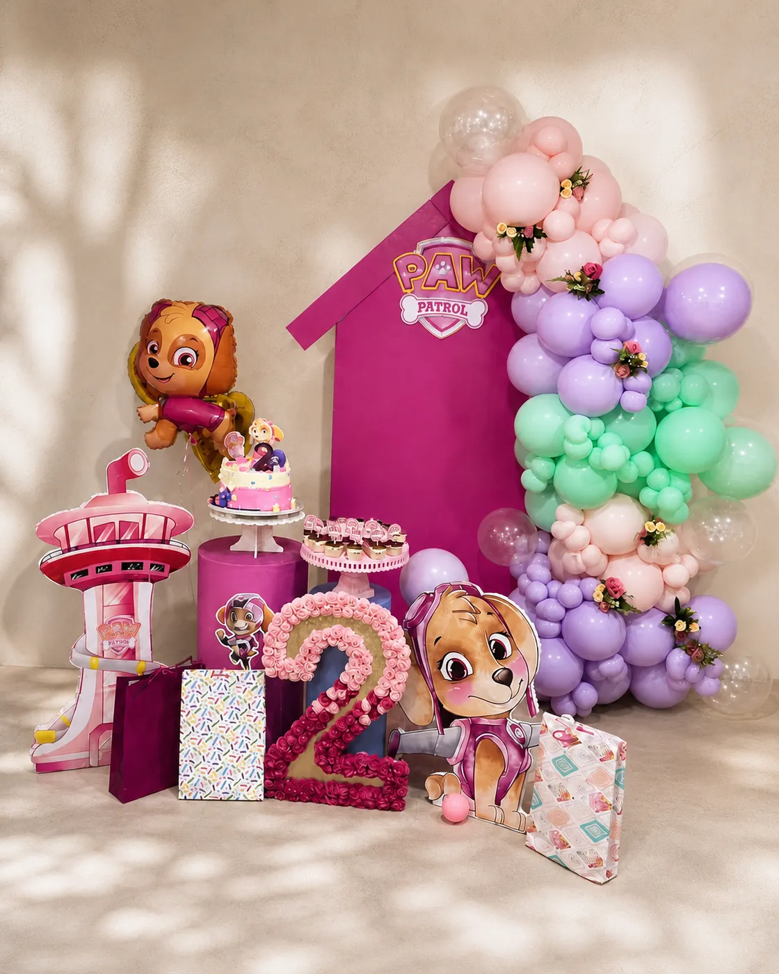 Celebración infantil completa en rosa, lila y verde con mesa de tarta y guirnalda de globos