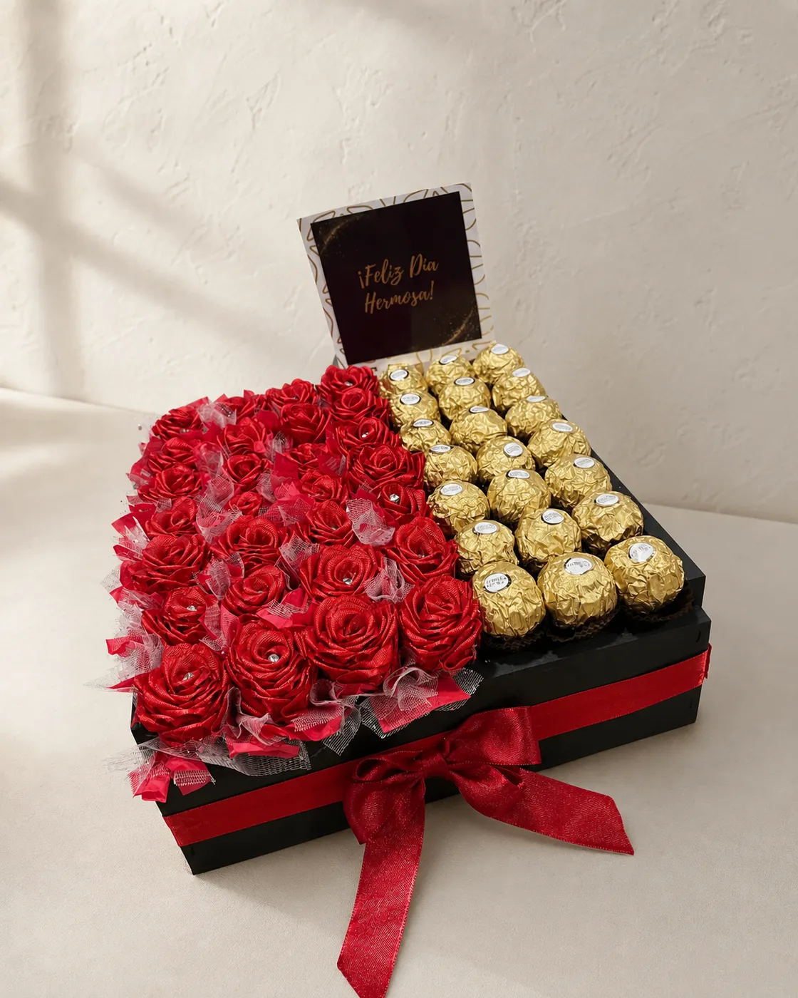 Caja de rosas rojas y bombones dorados con lazo de satén